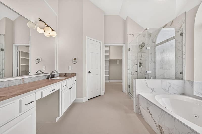 Primary bathroom with a glass shower and a soaking tub in marble tile