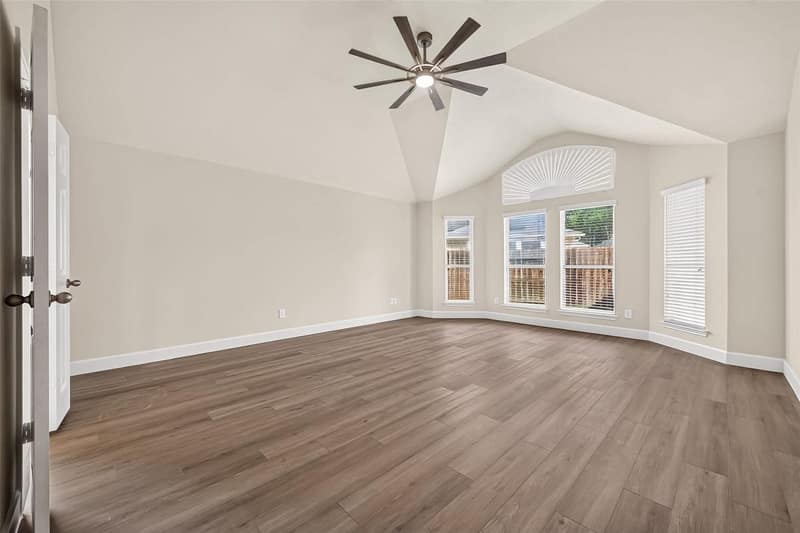 Primary bedroom with a vaulted ceiling and an arched window
